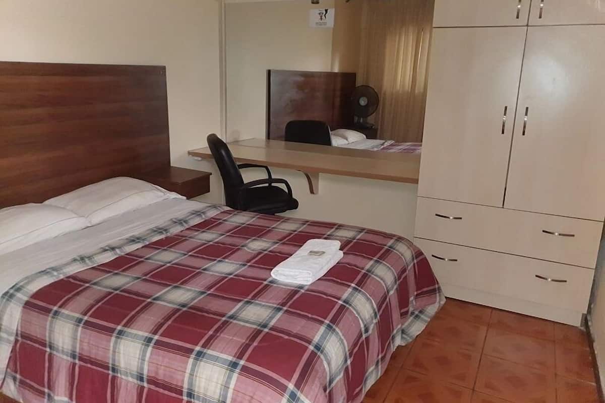 A bedroom with a bed, a desk, a chair, and a wardrobe.