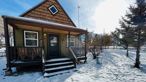 Une cabane en bois avec un porche à l’avant, une porte et une petite fenêtre.