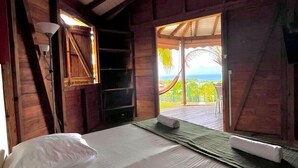Una habitación con una cama, ventilador de techo y vistas al exterior.