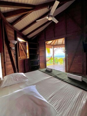 Ein Zimmer mit einem Bett, einem Deckenventilator und Blick ins Freie.