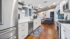 A modern kitchen with white cabinetry, stainless steel appliances, and a wooden floor.