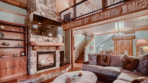 A cozy living room with a stone fireplace, wooden beams, a staircase, and a comfortable seating area. - Book 3+4th FREE Amazing views, Hot Tub, Pool Table, Hot Springs, Moose sightings (Fairplay)