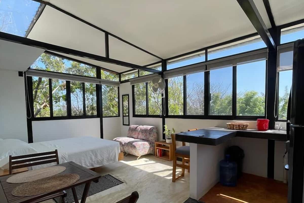 Une pièce moderne, à aire ouverte, comprenant un lit, un coin salon et une petite cuisine.
