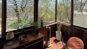 Une pièce chaleureuse avec de grandes fenêtres, un banc en bois, une chaise et un radiateur.