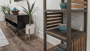 Ein modernes Wohnzimmer mit Holzboden, einer schwarzen Unterhaltungsanlage und einem schwarzen Fernseher an der Wand.