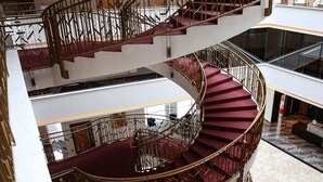 A multi-level interior with a central spiral staircase, marble flooring, and glass railings. - Lakeside Hotel (Prizren)