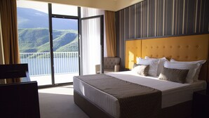 A hotel room with a large bed, a view of the mountains, and a balcony. - Lakeside Hotel (Prizren)
