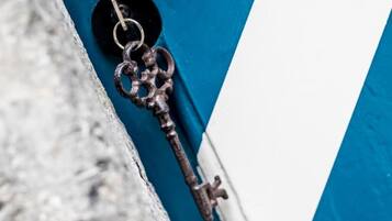 Primer plano de una llave vieja y oxidada colgada en una puerta azul y blanca.