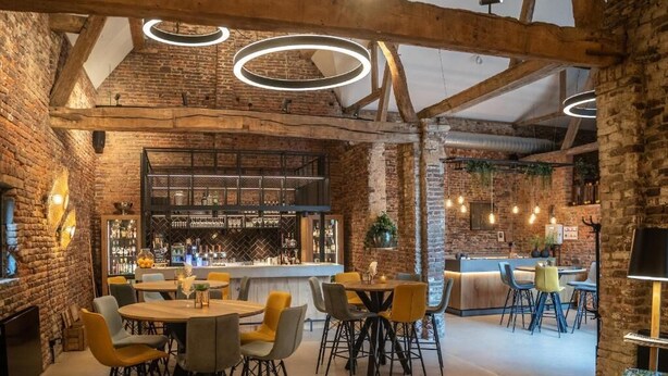 Un interior rústic amb parets de maó descobert, una zona de bar i seients moderns.