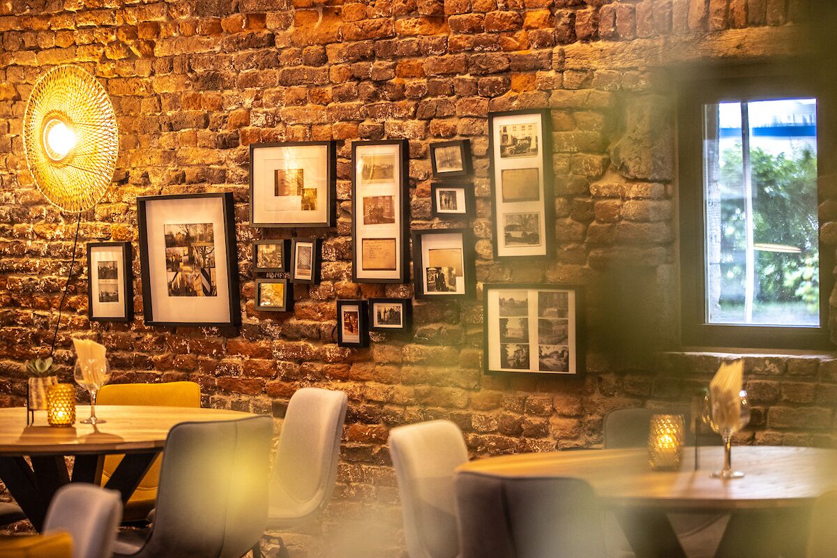 Un comedor con pared de ladrillo, cuadros enmarcados y una mesa con sillas.
