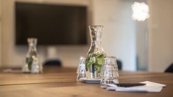 Een houten tafel met glazen vaasjes en een enkel bord, een zwart object en een witte servet.