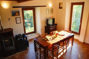 Ein Essbereich mit Holztisch, Stühlen, einem Fernseher und einer Küche mit Herd und Backofen.