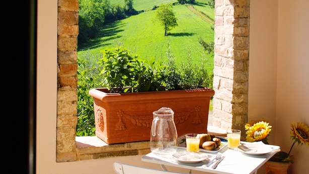 Una mesa con alimentos para el desayuno, vistas a colinas verdes y una planta colgante.
