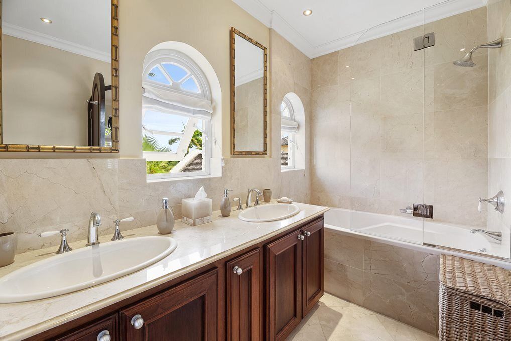 Une salle de bain avec deux lavabos, un grand miroir et une baignoire.
