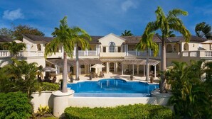 A large, two-story building with a swimming pool surrounded by palm trees. - Wild Cane Ridge 2 by Island Villas (Westmoreland)