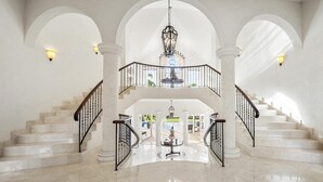 A grand, multi-level interior with marble stairs, arched ceilings, and a central chandelier. - Wild Cane Ridge 2 by Island Villas (Westmoreland)