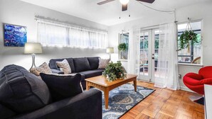 A living room with a ceiling fan, a sofa set, a coffee table, and a red chair. - Gator Getaway ~ close to UF & hospitals (Gainesville)