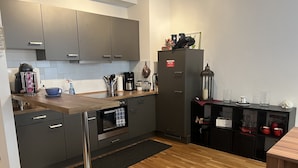 Una cocina moderna con gabinetes grises, encimera de madera, horno integrado y cafetera.