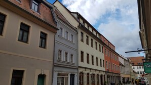 Una hilera de edificios históricos con ventanas de arco y una calle adoquinada.
