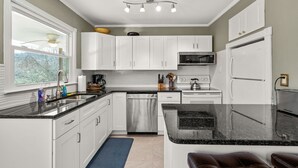 A modern kitchen with white cabinets, a black countertop, and stainless steel appliances.