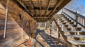 A wooden cabin with a covered porch and wooden stairs leading to a higher level.