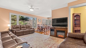 A living room with a fireplace, leather sofas, a dining table, and a TV.