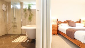 A modern bathroom with a glass shower enclosure, a freestanding bathtub, and a hand soap dispenser. - Larch Barn (Helston)