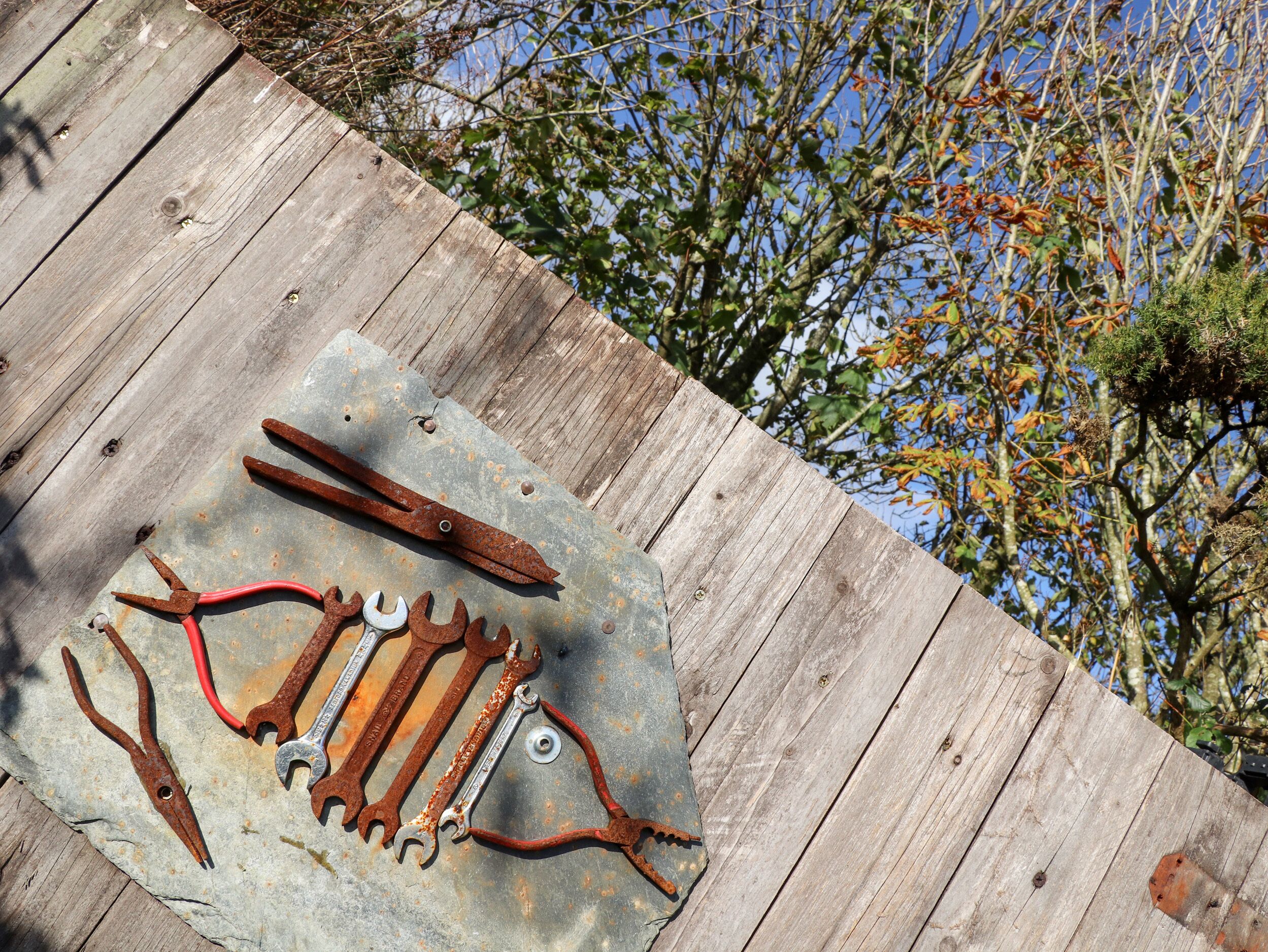 A wooden deck with a metal plate holding various rusted tools.