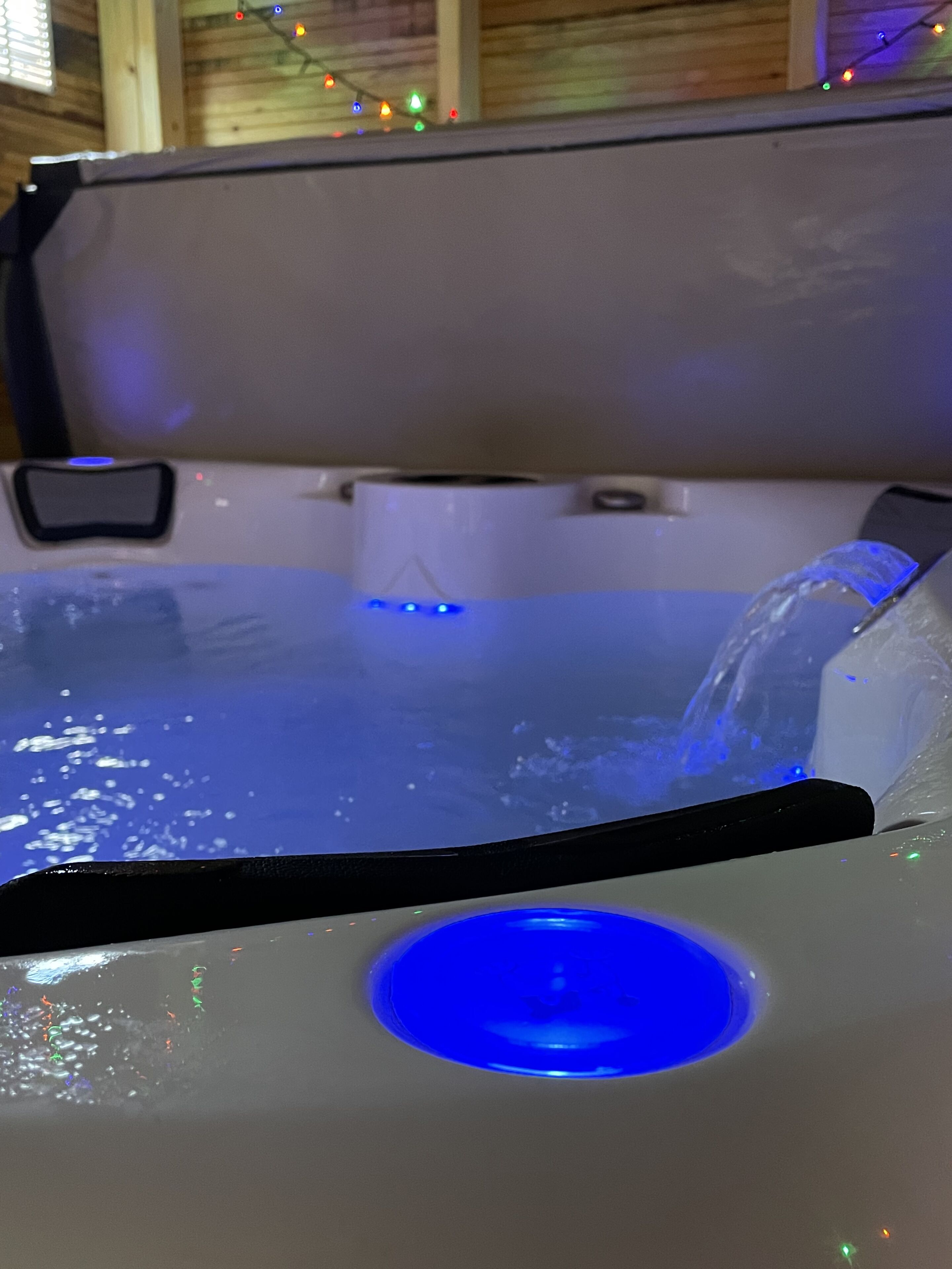 A hot tub with a blue light and a water feature.