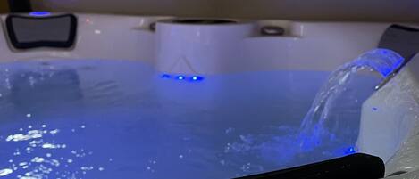 A hot tub with a blue light and a water feature.