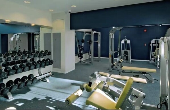 A modern gym with various weightlifting equipment, mirrors, and a bench. - Nautical 2 Bdrm with Ocean Views (Marina del Rey)