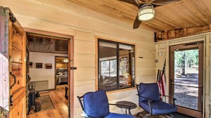 A wooden cabin interior with two blue chairs, a small table, and a ceiling fan. - Deck & Grill: Pet-Friendly Lakeside Cabin (Lakeside)