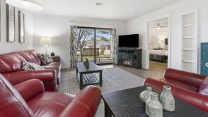 A living room with a red leather sofa, a dark wooden coffee table, and a flat-screen TV. - 2 bedroom, 2 bath ground floor condo with indoor pool minutes from Branson strip (Branson)