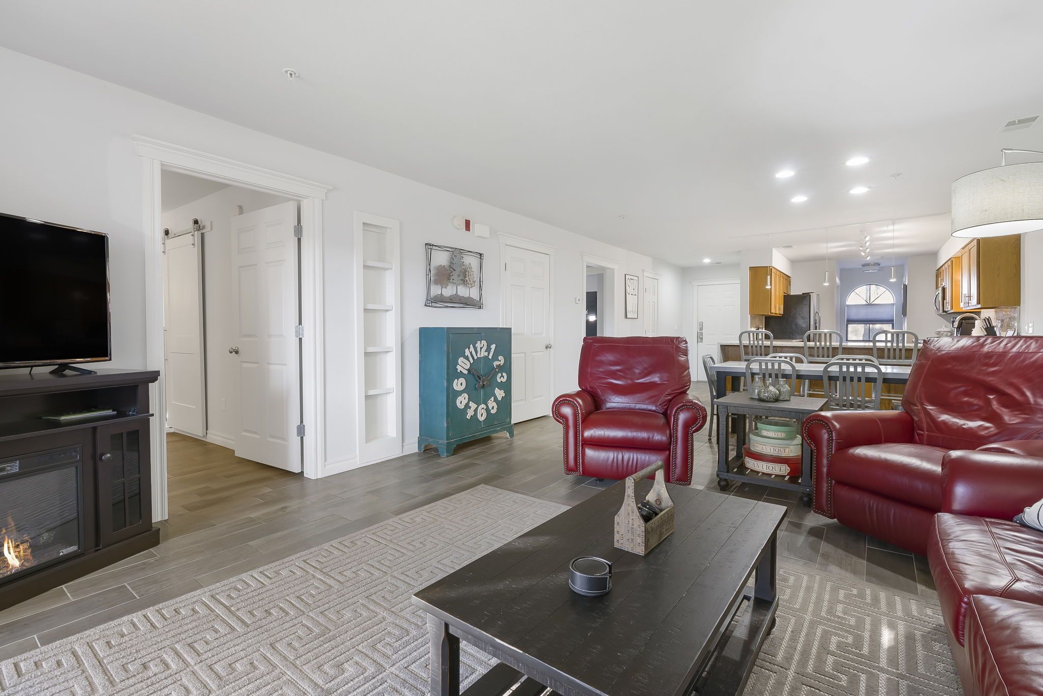 A living room with a fireplace, a red leather sofa, a coffee table, and a television.