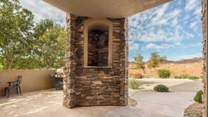 A stone fireplace with a view of a desert landscape.