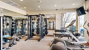 A gym with various exercise equipment, mirrors, and a treadmill.