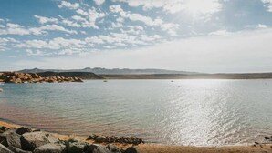 A calm lake with a sandy beach and rocky shoreline.