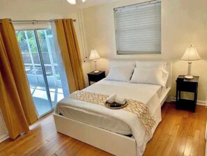 Relax in comfort with a large bed, two nightstands, and a sliding glass door leading to an outdoor area.