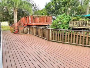 Surrounded by lush greenery, this outdoor deck offers a tranquil retreat with a small elevated platform and a railing.