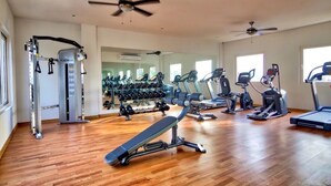 A spacious gym with various exercise equipment, including treadmills, elliptical machines, and free weights. - Condominios Z (Puerto Vallarta)