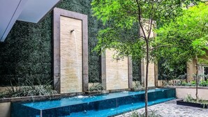 A modern outdoor pool area with a rectangular pool, surrounded by a tiled walkway and bordered by planters with greenery. - Condominios Z (Puerto Vallarta)