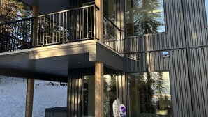 Un bâtiment moderne à deux étages, doté d’un balcon et de grandes fenêtres qui reflètent les arbres.