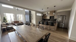 Une cuisine moderne avec une table à manger en bois, des tabourets de bar et un four encastré.