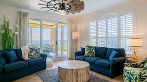 A modern living room with two sofas, a round coffee table, and a ceiling fan. - Beach Colony West #1D | Large Patio & Many Community Amenities (Perdido Key)