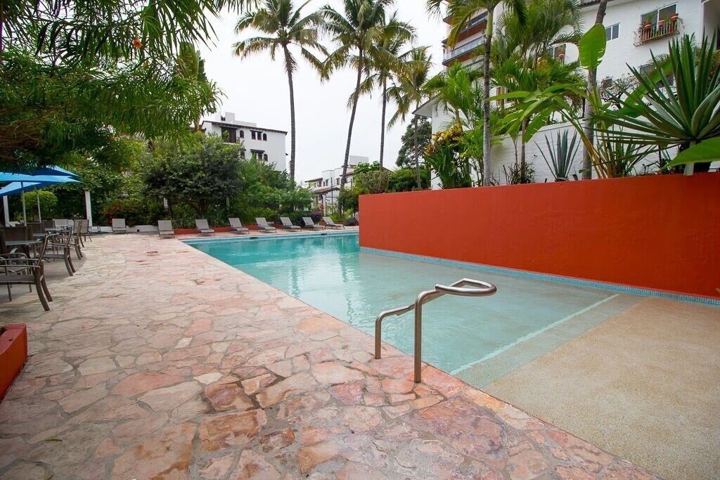 Une piscine avec des chaises longues et un chemin en pierre.