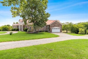 A large, two-story house with a stone facade, a red roof, and a white garage door. - Luxurious 5-Bed Escape in Heart of Bourbon Trail (Bloomfield)