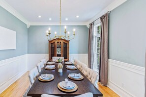 A dining room with a dark wooden table set for six, a chandelier, and a wooden cabinet with glass doors. - Luxurious 5-Bed Escape in Heart of Bourbon Trail (Bloomfield)