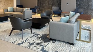Uma sala de estar moderna com um sofá, cadeiras, uma mesa de centro e um tapete estampado.