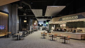 Um espaço amplo e interno com diversos arranjos de assento, área de bar e um balcão da Starbucks.