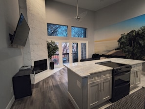 Una cocina moderna con una isla grande, electrodomésticos integrados y un televisor de pantalla plana en la pared.